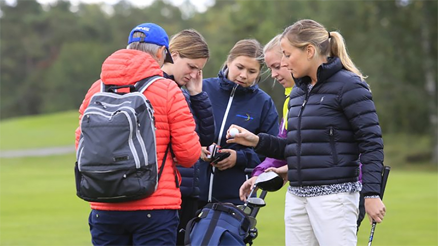 En grupp står och kollar på en golfboll
